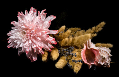 A close-up horizontal still life featuring a pink chrysanthemum, a bouquet of dried golden grasses...