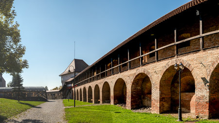 Targu Mures, Romania - october 17. 2025. Sunlit medieval brick fortress walls with arcades and wooden upper walkway in Targu Mures, Transylvania, Romania, showcasing historical architectureのeditorial素材