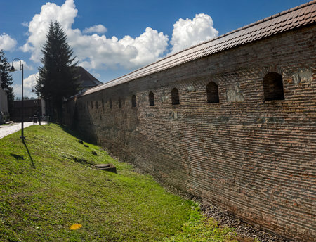 Targu Mures, Romania - october 17. 2025. Sunlit medieval brick fortress walls with arcades and wooden upper walkway in Targu Mures, Transylvania, Romania, showcasing historical architectureのeditorial素材