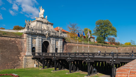 Alba Iulia, Romania - October 19.2025. An ornate baroque stone gate with statues stands at the end of a historic wooden bridge within the Alba Carolina Citadel in Romaniaのeditorial素材
