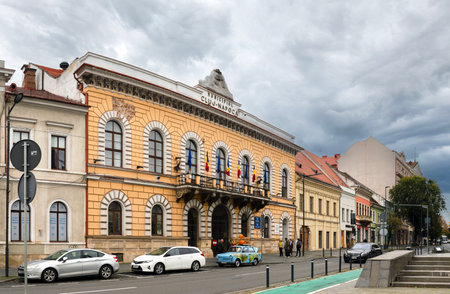 Cluj-Napoca, Romania - October 18.2025. A wide view of the historic Old Town Hall building with arched windows and flags on Eroilor Avenue in Cluj-Napoca, featuring a vintage blue car parked out frontのeditorial素材