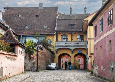 SighiÈoara, Romania - 10/21/2025. Ancient stone gate of the Tailors Tower overlooking a winding cobblestone road within the historic UNESCO world heritage site of Sighisoara Romaniaのeditorial素材