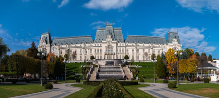 IaÈi, Romania - October 23.2025. Wide panoramic view of the Neo-Gothic Palace of Culture in Iasi Romania featuring the lush Palas Public Garden with fountains and autumn trees under a bright blue skyのeditorial素材