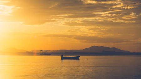 A boat in the sea on sunset time and mountain sceneの写真素材