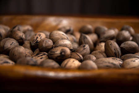 Raw in shell whole Pecan nuts in a wooden bowl on a wood tableの写真素材