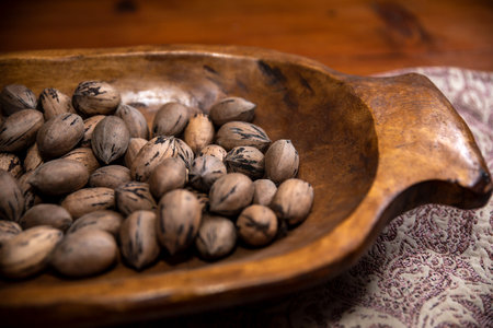 Raw in shell whole Pecan nuts in a wooden bowl on a wood tableの写真素材