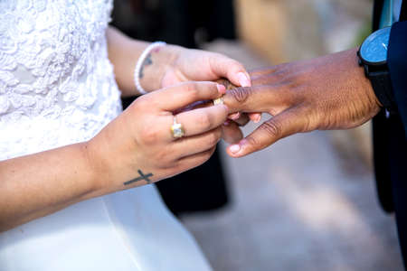Bride putting ring on grooms`s finger closeup of hands and ringの写真素材