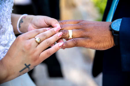 Bride putting ring on grooms`s finger closeup of hands and ringの写真素材