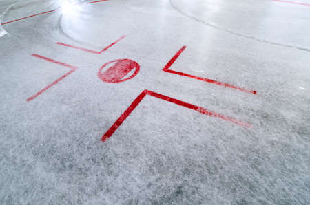 Hockey rink with faceoff spot on freshly resurfaced ice with marks of waterの写真素材