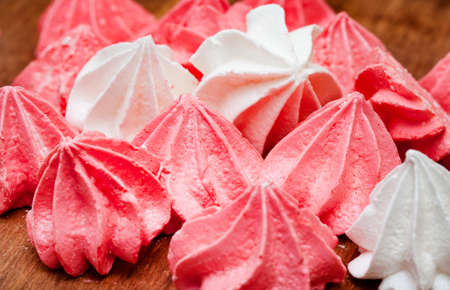 pink and white meringues on wooden surface with crumbs and copy spaceの写真素材