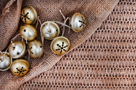 Rustic golden Christmas bells on hessian and rustic background