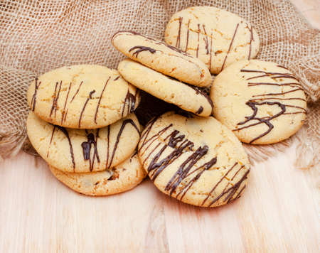 Chocolate chip biscuits, freshly baked with chocolate drizzle on rustic farm style tableの写真素材