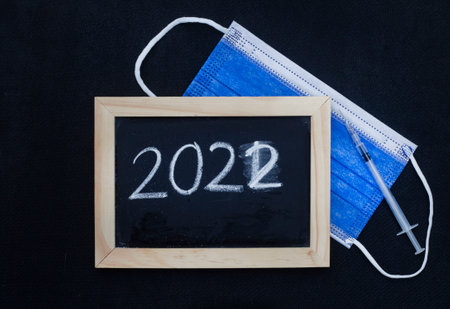 blackboard with 2022 written on it with blue surgical face maskの写真素材