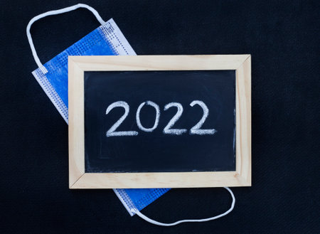 blackboard with 2022 written on it with blue surgical face maskの写真素材