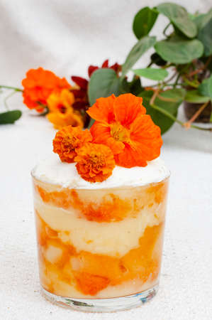 Orange peach and custard trifle serving with bright orange flowersの写真素材