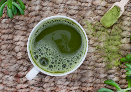 Matcha tea on rustic surface with scoop of powdered matcha