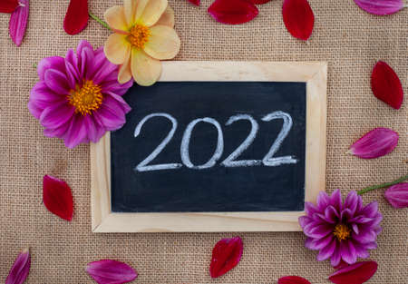 2022 written on chalk board with fresh flowers on a rustic burlap backgroundの写真素材