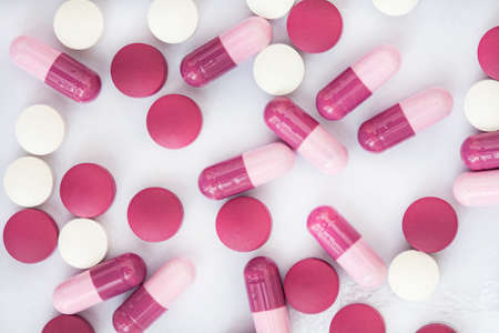 pink and magenta colored pills and medication on white backgroundの写真素材