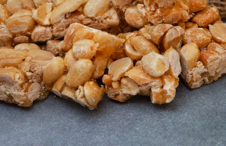 Peanut brittle, an old school sweet favorite, cut into small bars on rustic type surface with copy...