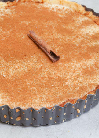 Traditional South African milk tart freshly baked and in tin. Mottled grey and rustic surface with copy spaceの写真素材