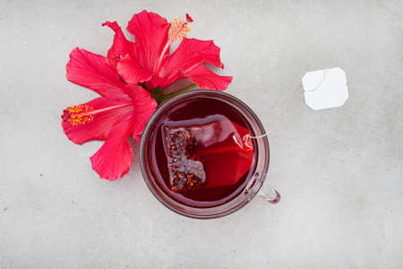 Bright and flavorful hibiscus tea in a glass cup, with hibiscus flower and copy spaceの写真素材