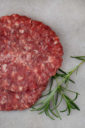 Raw free range 100% beef burger patties on mottled grey with copy spaceの写真素材