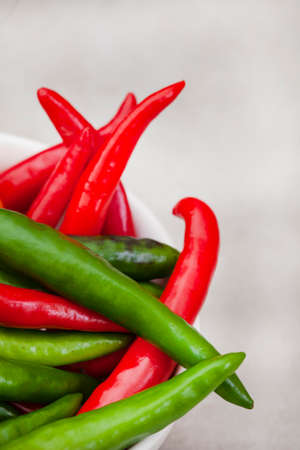 bright small red and green chilies on light grey with copy spaceの写真素材