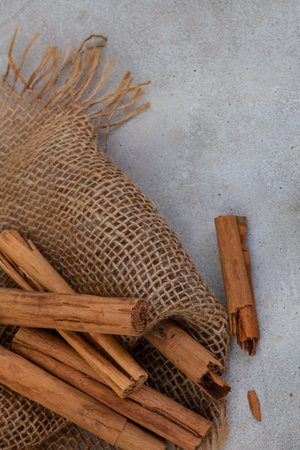 Whole cinnamon sticks on mottled grey surface with burlap and copy space.の写真素材
