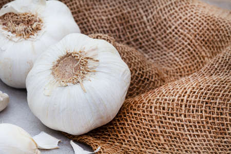 garlic bulb and cloves on rustic and mottled gray surfaceの写真素材