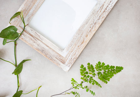 mottled grey surface with distressed wooden frame and botanical elements with copy space
