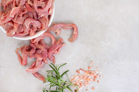 raw and thinly sliced beef strips with rosemary and salt with copy spaceの写真素材