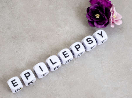 Epilepsy written in dice with paper flowers on mottled grey with copy spaceの写真素材