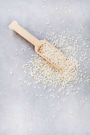 Plain sesame seeds with wooden scoop on mottled grey with copy spaceの写真素材