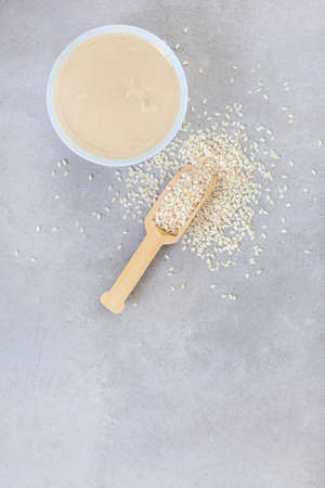 Pure sesame tahini with sesame seeds on mottled grey with copy spaceの写真素材