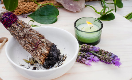 Smudge stick burning with smoke on a table with plants, candle and crystalの写真素材