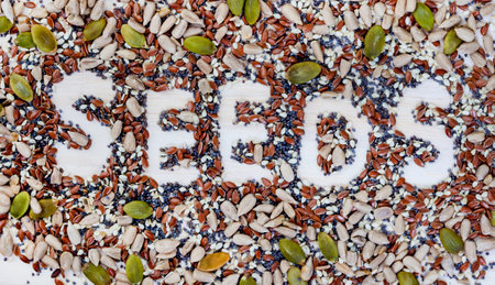 The word SEEDS written with seeds on a white wooden background.