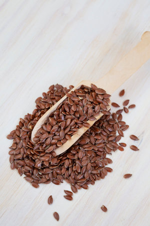 Flax seeds in a wooden spoon on a white wooden background.の写真素材