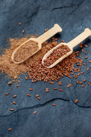Flax seeds and linseed in wooden spoons on dark backgroundの写真素材