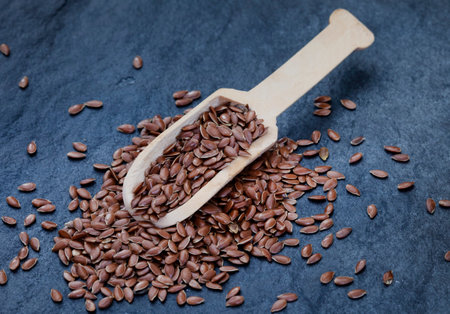 Flax seeds in wooden spoon on dark background. Healthy food.の写真素材