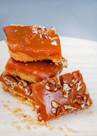 Pieces of shortbread topped with caramel and nuts on a wooden board. Selective focus.の写真素材