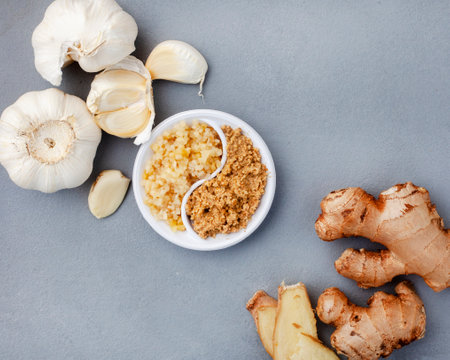 garlic and ginger, whole and crushed flat lay on grey