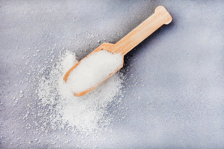 Wooden scoop with white sugar on mottled gray surfaceの写真素材