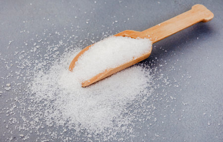 Wooden scoop with white sugar on mottled gray surfaceの写真素材