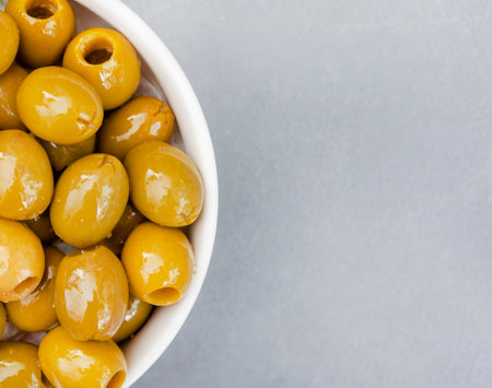 Green olives in a bowl on grey background. Top view.の写真素材