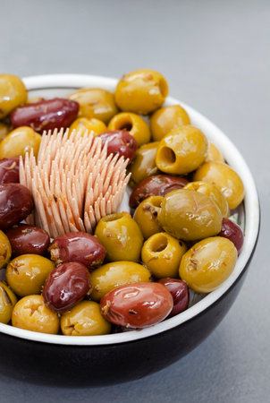 Green and red olives in a bowl on a grey background.の写真素材
