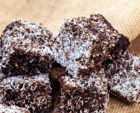 Chocolate lamingtons with coconut flakes on burlap background.の写真素材
