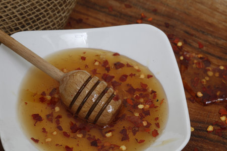 Hot honey or chili honey with honey dripper on rustic wooden tableの写真素材