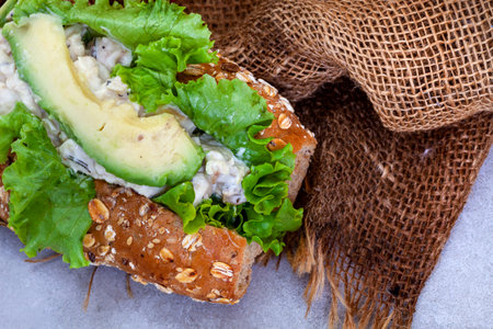 Sandwich with salmon, avocado and lettuce on sackcloth, top viewの写真素材
