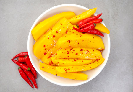 Sliced mango with chili peppers in a bowl on gray backgroundの写真素材