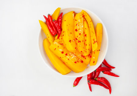 Sliced mango with chili peppers in a bowl on white backgroundの写真素材